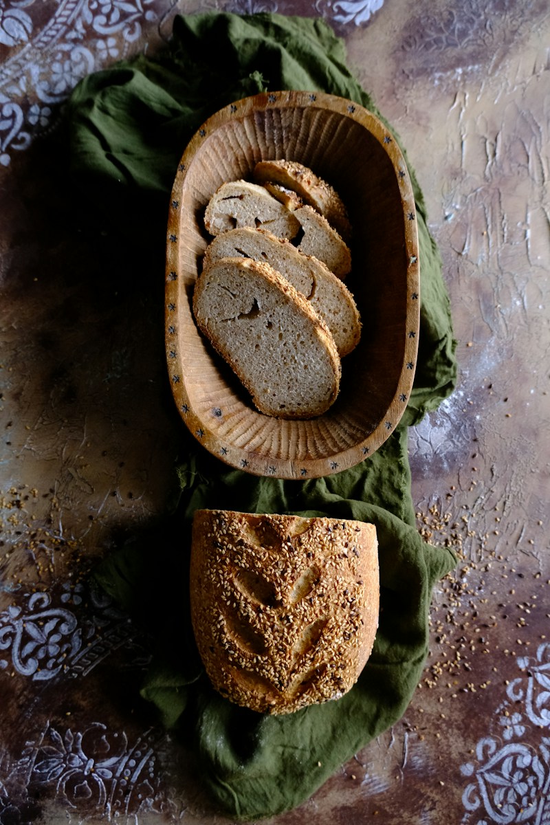 a wooden bowl filled with bread next to a loaf of bread